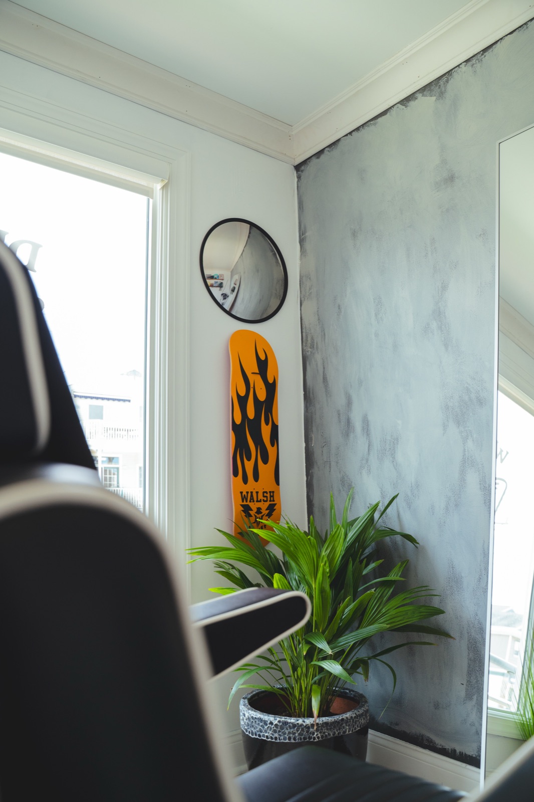 Inside Dead Low Studio — black salon chair, plant, and flame skim board against the textured wall